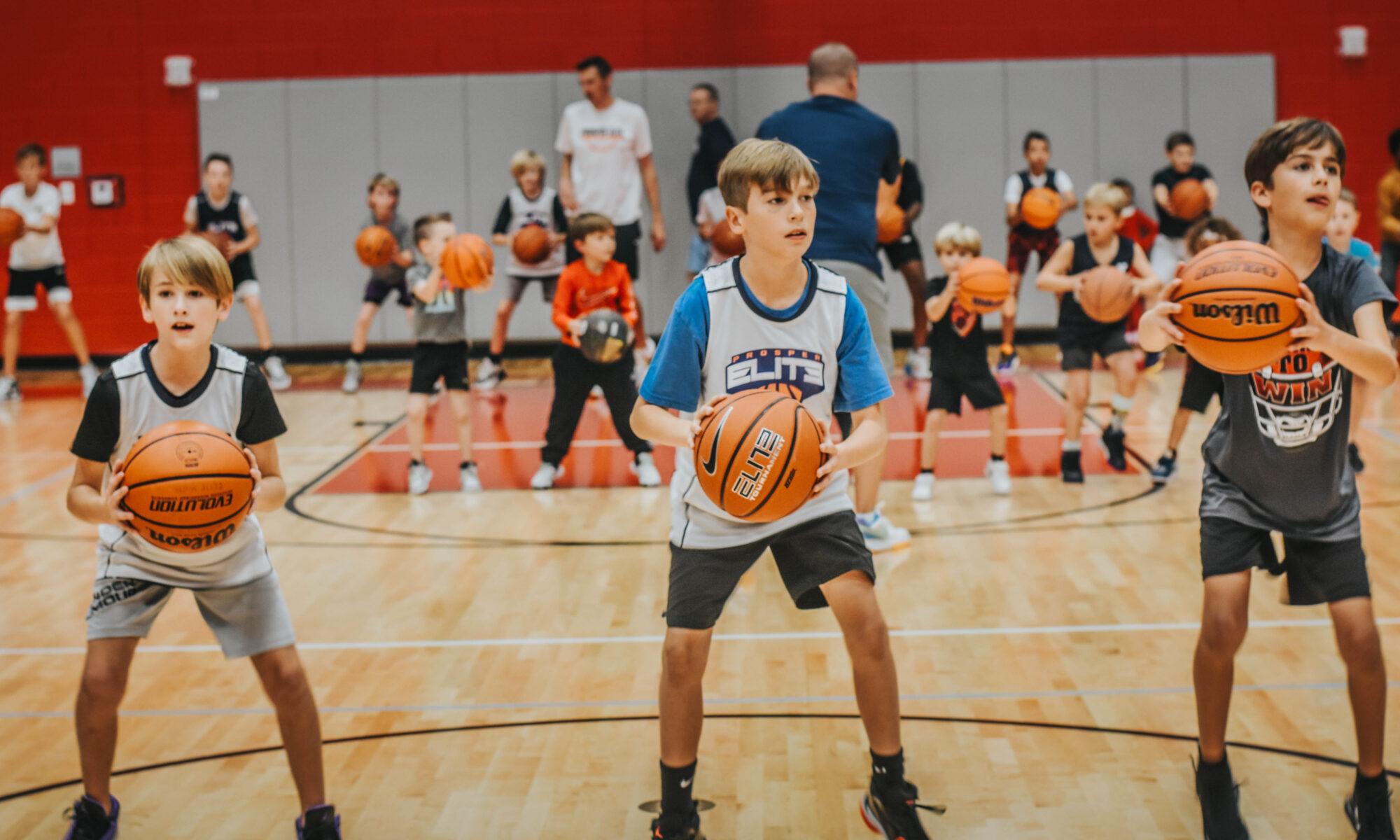 Three young athletes practicing at Elite Hoops Academy™ weekly Skills & Drills session, focused and engaged in basketball training.