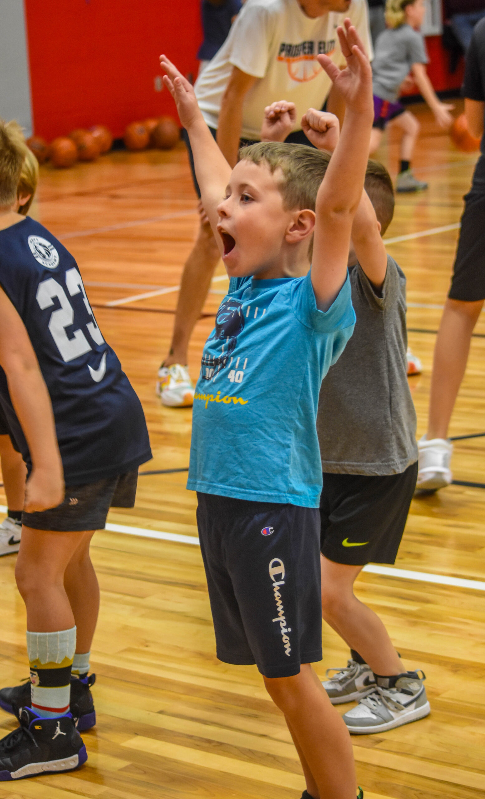 A young kindergarten Elite Hooper celebrating an accomplishment with a joyful expression, embodying the fun and excitement of youth basketball